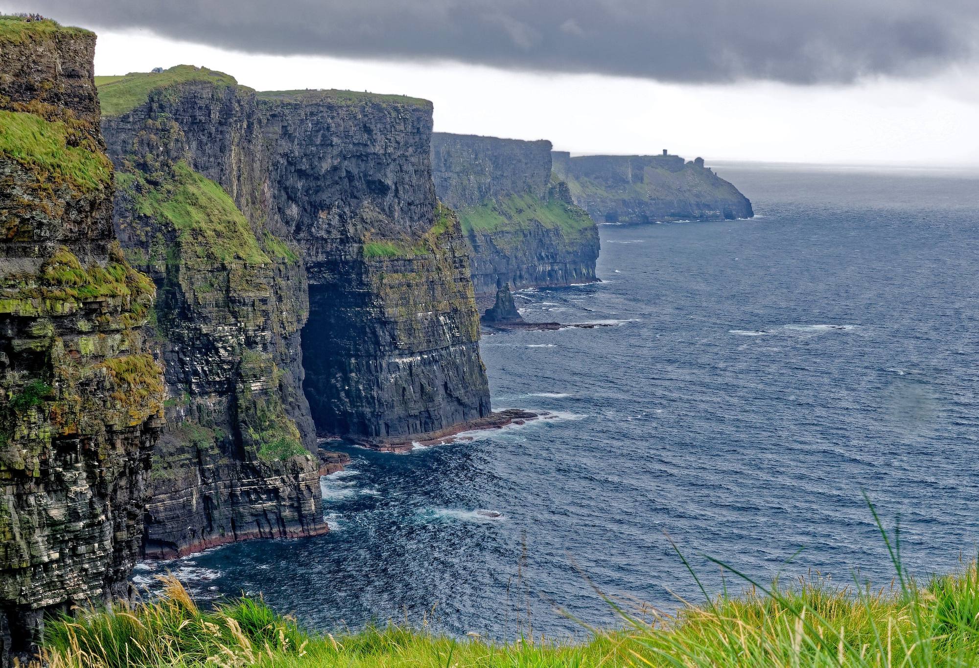 The Cliffs of Moher falling into the Atlantic under a grey sky